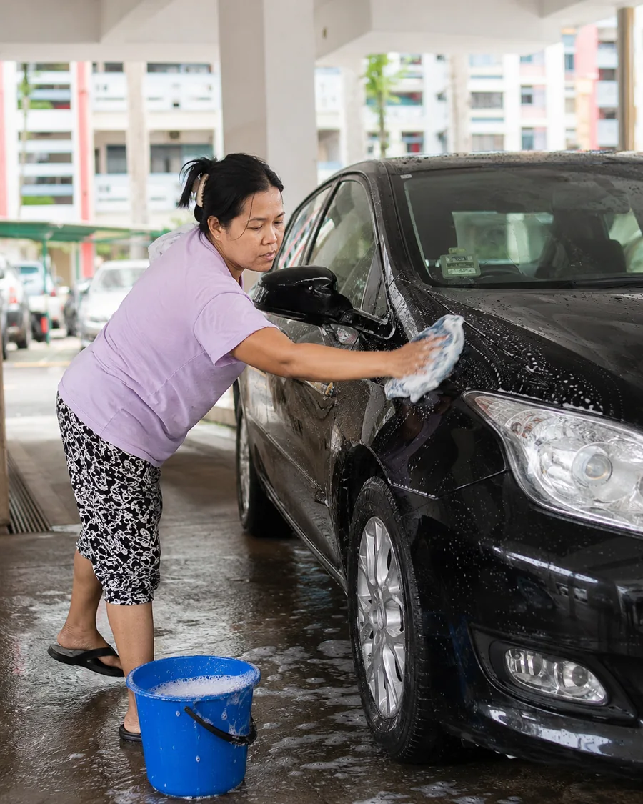 Helper washing car in HDB carpark